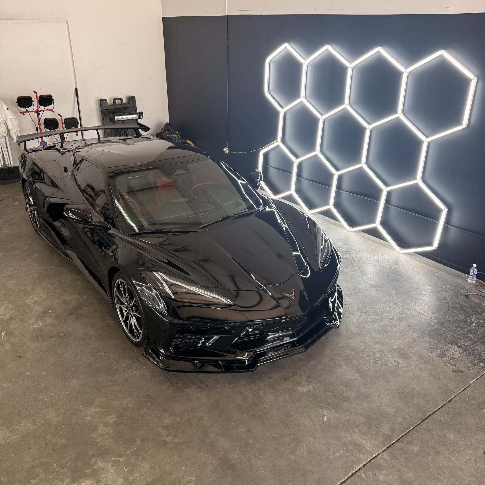Black Corvette detailed under studio lighting after PPF install